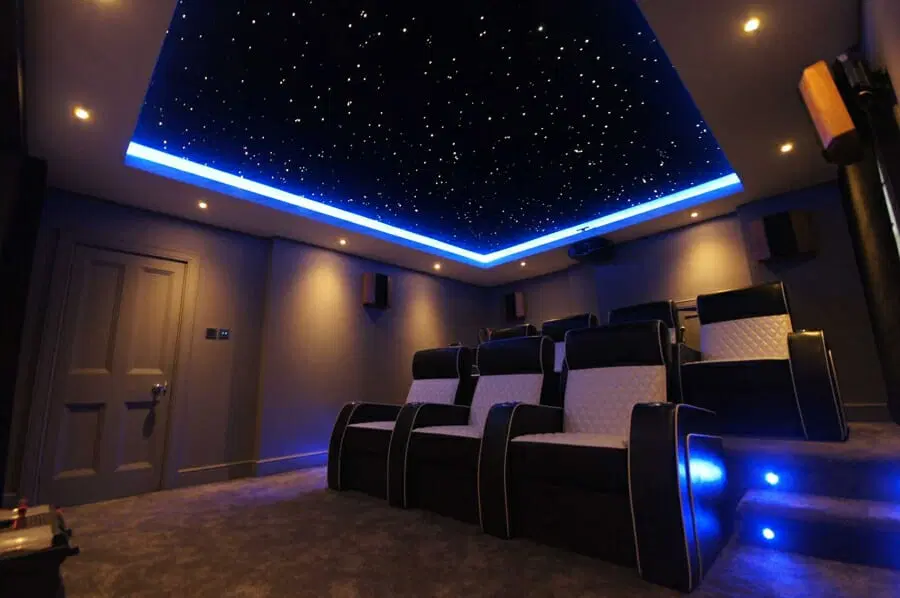 Stretch ceiling with starry night sky design and blue LED backlighting in home theater - Florida installation